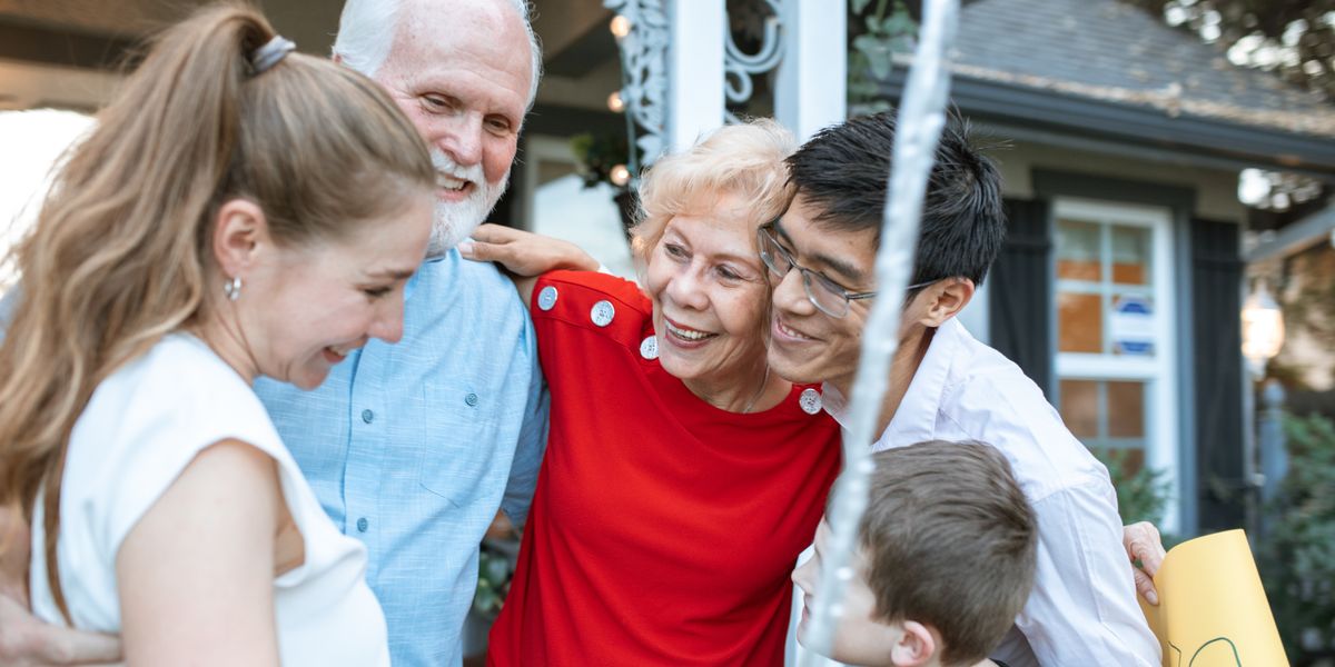 An older couple embraced by their adult children and grandchildren