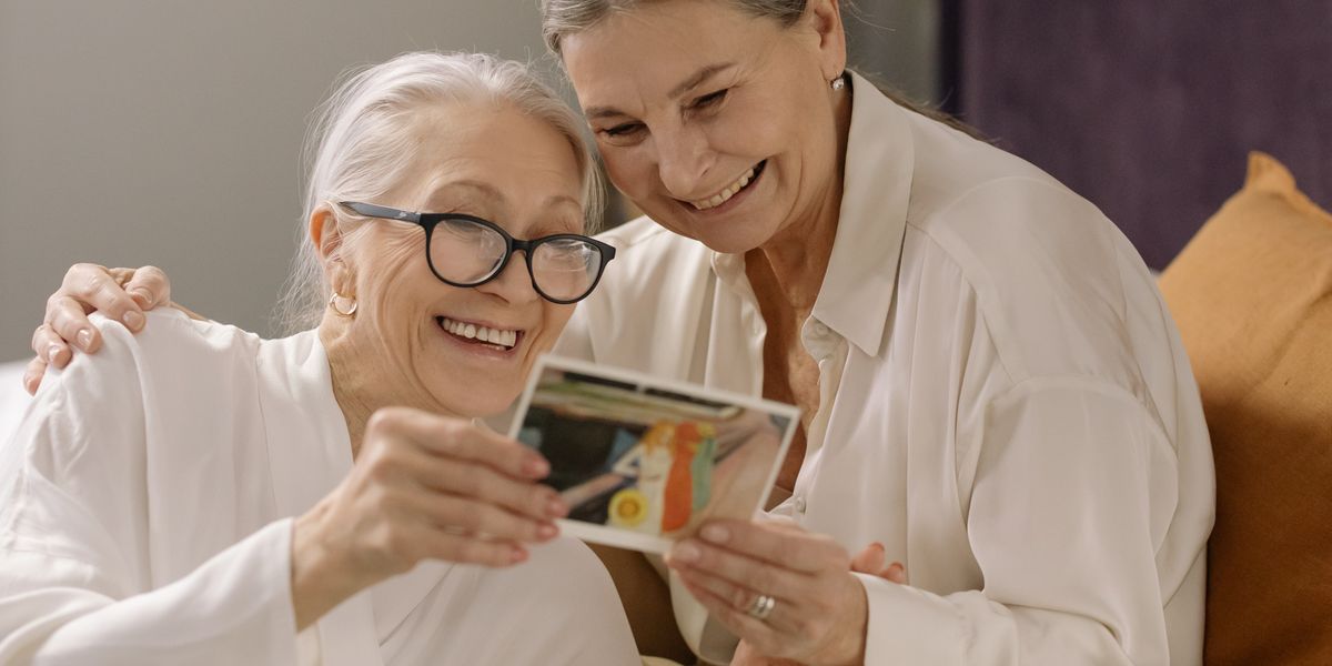 Two residents smiling together over an old photograph